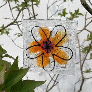 Blumenornament auf quadratischer Glasscheibe mit zwei zueinander verdrehten Glasblumen