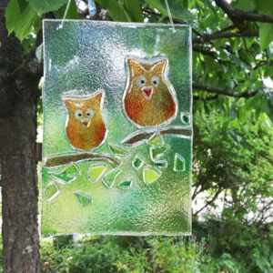 leuchtendes Glasbild, Sonnenfänger mit bunten Eulen als Gartendekoration oder Geschenk. Fensterdekoration in Fusingtechnik