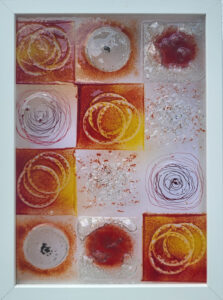Dieses Glasbild besteht aus einer Komposition von zwölf quadratischen Glaselementen, Jedes Segment wirkt wie ein kleines Fenster in eine eigene Welt, wobei die Kombination aus geschmolzenem Glas, Luftblasen und eingeschmolzenen Elementen eine spannende Tiefenwirkung